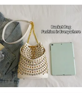 Dettaglio borsa a secchiello bianca stile punk con borchie e cristalli vicino al tablet