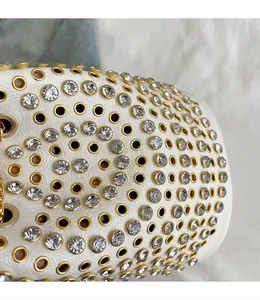 Dettaglio macro di borsa bianca con borchie dorate e strass scintillanti incastonati