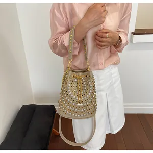 Modella con borsa a secchiello beige alla moda stile punk con strass e borchie dorate
