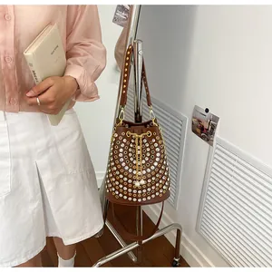 Dettaglio della borsa a secchiello punk con borchie dorate e strass scintillanti.