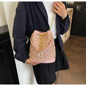 Elegante borsa a secchiello rosa con borchie dorate e cristalli indossata dal modello.