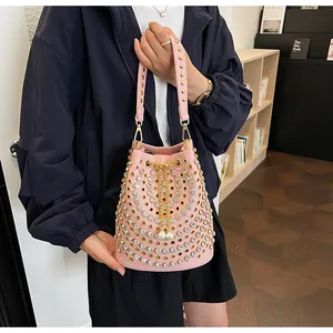 Vista dettagliata della borsa a secchiello rosa stile punk con borchie dorate e strass su modella