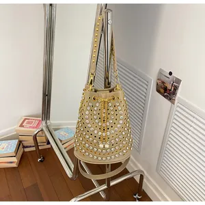 Dettaglio borsa a secchiello beige con strass scintillanti e borchie dorate