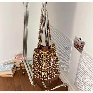 Dettaglio borsa a secchiello marrone stile punk con strass e borchie dorate elaborate