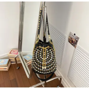 Dettaglio borsa a secchiello nera stile punk con borchie dorate e strass brillanti.