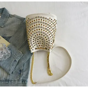 Dettaglio borsa a secchiello bianca stile punk con strass scintillanti e tracolla a catena.