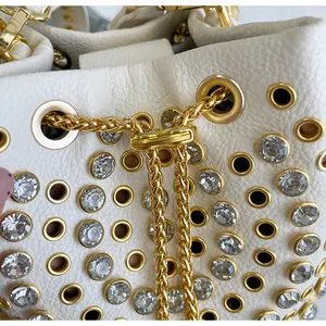 Dettaglio borsa in pelle bianca stile punk con borchie dorate e strass luccicanti.