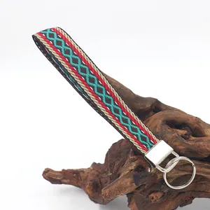 Portachiavi etnico ricamato con motivo geometrico rosso e verde acqua su supporto legno