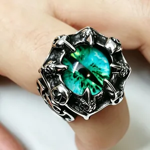 Macro detail of retro punk dragon claw ring with green eye in stainless steel