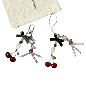 Ciondolo per telefono e borsa con ciliegie e fiocco con perle a cuore e stelle, rosso.