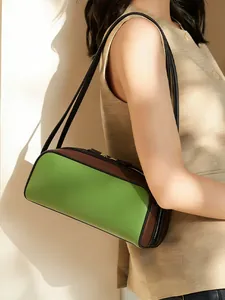 Primer plano de un bolso baguette bicolor verde y marrón elegante para mujer puesto al hombro.