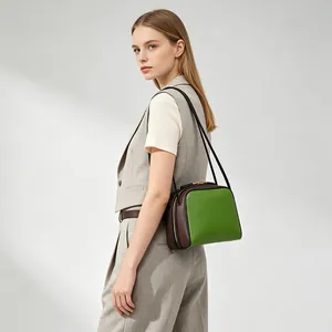 Modelo que lleva un bolso baguette bicolor verde y marrón de estilo minimalista
