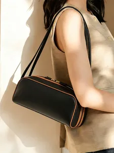 Elegante bolso baguette negro con ribetes marrones en contraste y detalles dorados.