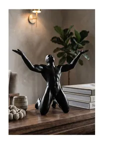 Detail view of a black Nordic male figurine kneeling with open arms on a desk.