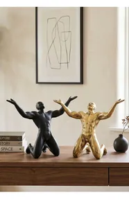 Detailed view of artistic male figure sculptures in black and gold on wooden desk