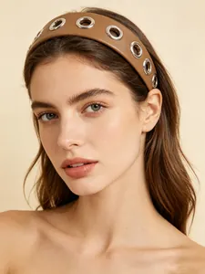 Detail shot of a stylish wide brown PU leather headband with silver metal eyelets on model.
