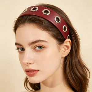 Close-up detail of a stylish burgundy PU leather headband with silver metal grommets