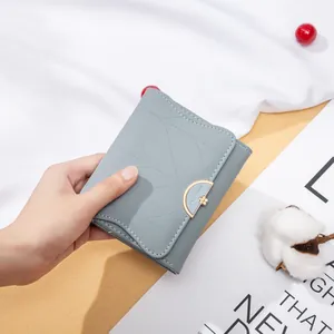 Dettaglio del portafoglio in pelle PU azzurro a tre ante tenuto in mano con stile
