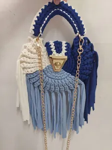 Detailed view of a handmade blue and white crochet bag with elegant tassels and gold chain.