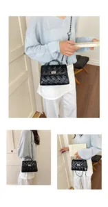 Sac bandoulière tissé noir élégant avec un fermoir rotatif argenté et une chaîne chic
