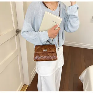 Vue détaillée d'un sac bandoulière marron tressé vintage avec un pull bleu ciel