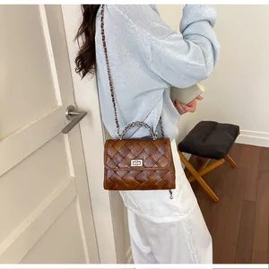 Vue détaillée d'un sac bandoulière marron tressé rétro porté avec un pull bleu clair