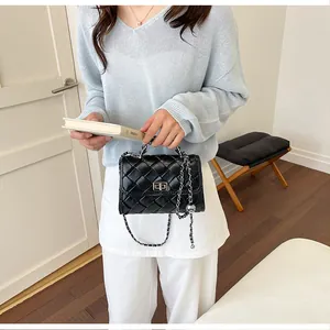 Détail d'un sac carré en cuir tressé noir avec bandoulière chaîne argentée sur mannequin