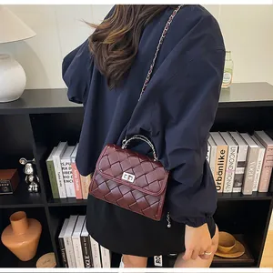 Gros plan sur un sac bandoulière tissé bordeaux avec chaîne argentée et fermoir métallique