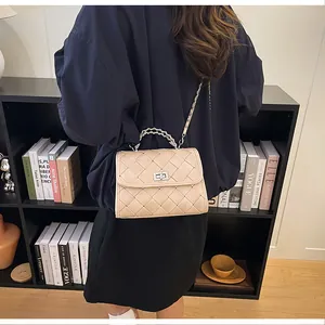 Vue détaillée d'un sac bandoulière tissé beige porté par un mannequin en intérieur