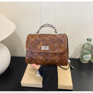 Gros plan d'un sac bandoulière en cuir tressé marron avec chaîne argent
