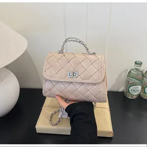 Gros plan d'un sac à main chic en cuir tressé crème avec sa poignée en chaîne argentée