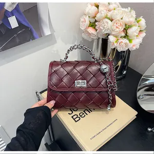 Détail d'un sac à main bordeaux en cuir tressé avec poignée en chaîne argentée
