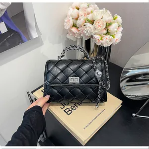 Sac à bandoulière tressé noir avec chaîne argentée présenté dans un décor élégant