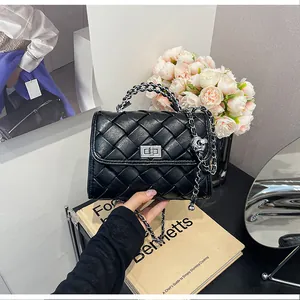 Détail d'un sac à main noir tressé avec chaîne argentée et fermoir pivotant élégant.