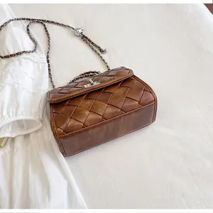 Vue détaillée d'un élégant sac bandoulière en cuir tressé marron avec une chaîne