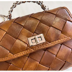Zoom sur la texture en cuir tressé marron d'un sac à main rétro avec fermoir argenté.