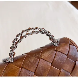 Gros plan d'un sac à main en cuir tressé marron avec poignée en chaîne argentée