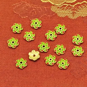 Close-up macro detail of green and red enamel flower spacers for DIY jewelry making