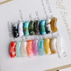 Primo piano di perle a tubo curvo in resina colorata per la creazione di gioielli fai da te