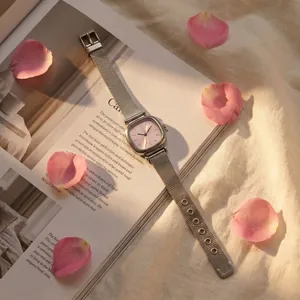 Detailed close-up of a silver mesh strap watch with a minimalist pink square dial