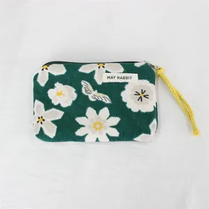 Detailed macro view of a green corduroy coin purse with floral patterns and a MAY RABBIT label
