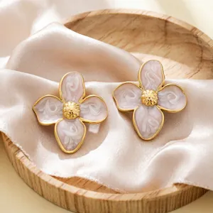 Gros plan d'élégantes boucles d'oreilles fleurs en émail rose vintage sur soie