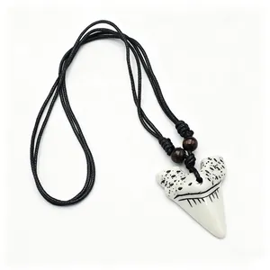 Détail d'un pendentif dent de requin en résine tribale avec cordon noir et perles en bois