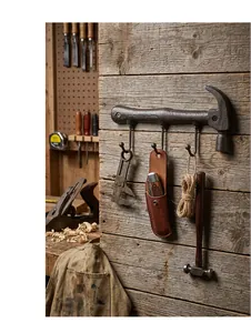 Detail of antique cast iron hammer-shaped wall hook mounted in a rustic tool workshop