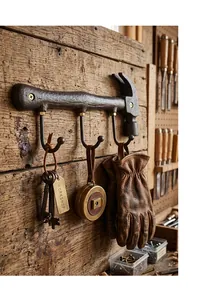 Rustic vintage hammer-shaped cast iron wall hook with three hangers in a workshop setting