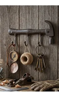Vintage cast iron hammer wall hook with three hangers on rustic wooden background