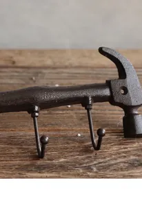 Close-up detail of a rustic cast iron hammer-shaped wall hook on a wooden background