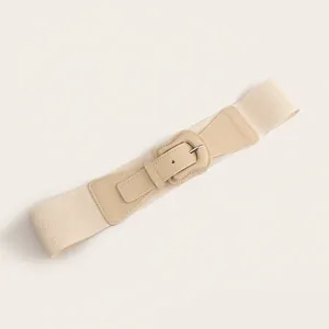 Detailed view of a wide elastic beige waist belt with an elegant buckle for coats
