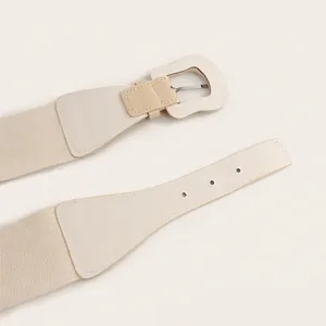 Detailed view of cream-colored elastic waist belt featuring textured leather and buckle.