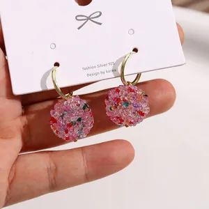 Dettaglio ravvicinato di orecchini a sfera con perline rosa e vivaci accenti colorati